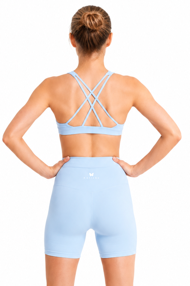 Person wearing a light blue sports bra and shorts set on a white background