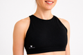 Black sports bra worn by a person on a light gray background