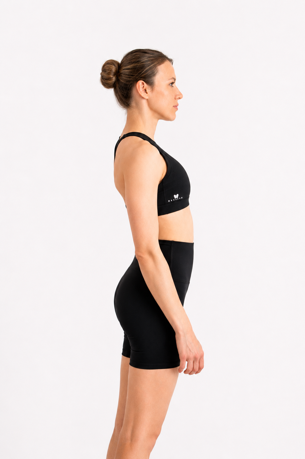 Woman wearing a black sports bra and shorts on a white background
